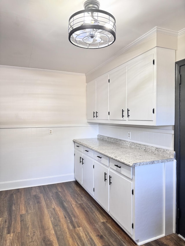 kitchen featuring white cabinets, dark hardwood / wood-style floors, light stone counters, and crown molding