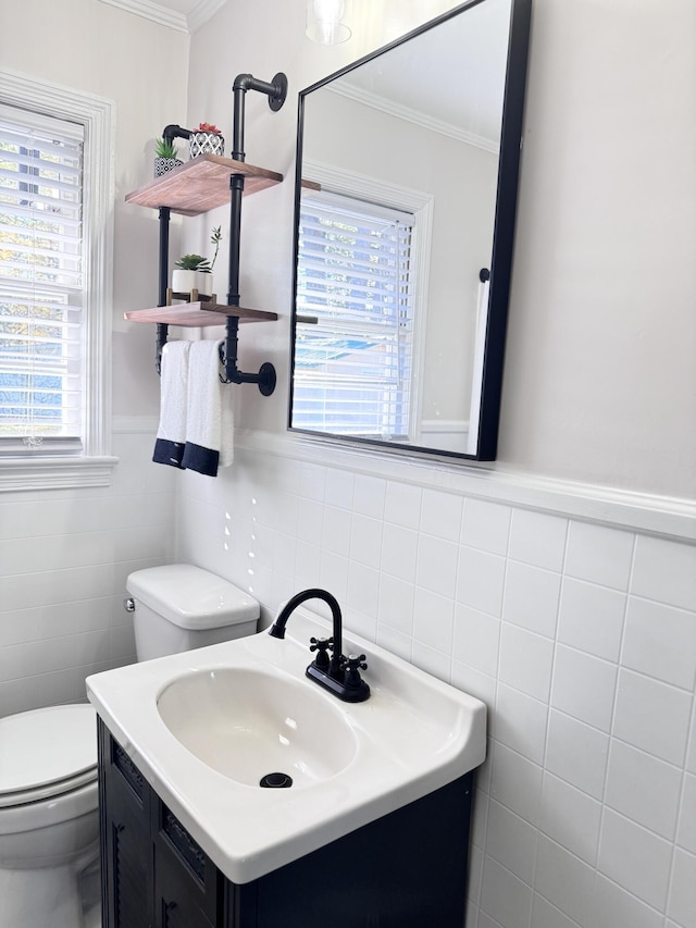 bathroom featuring vanity, toilet, crown molding, and tile walls