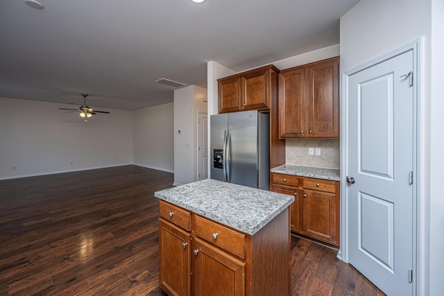 kitchen featuring decorative backsplash, a ceiling fan, stainless steel fridge with ice dispenser, dark wood-type flooring, and a center island