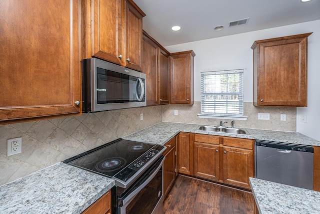 kitchen with visible vents, brown cabinetry, dark wood finished floors, stainless steel appliances, and a sink