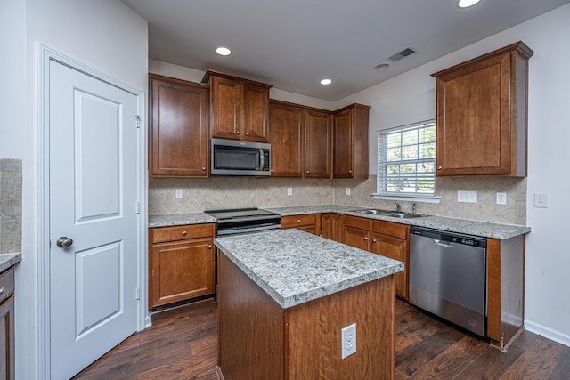 kitchen with appliances with stainless steel finishes, dark wood-style flooring, a kitchen island, and visible vents