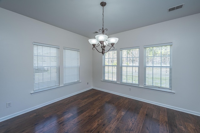 unfurnished room with baseboards, plenty of natural light, visible vents, and dark wood-type flooring