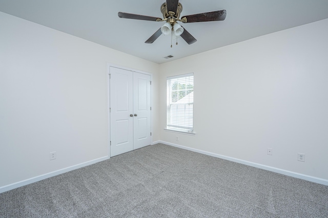 carpeted spare room featuring visible vents, ceiling fan, and baseboards