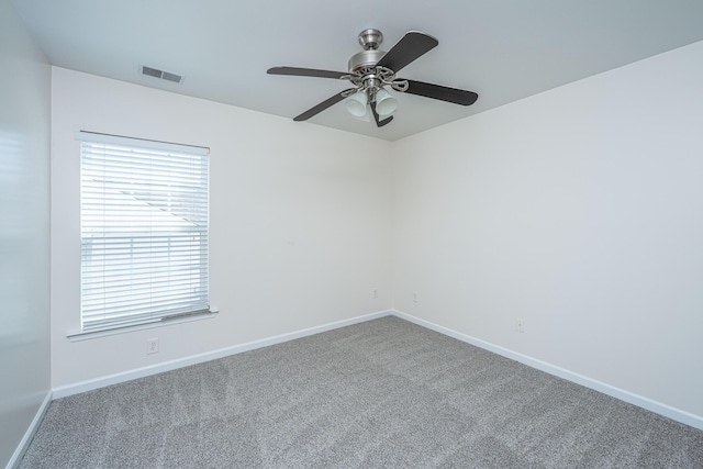 carpeted empty room with visible vents, baseboards, and ceiling fan