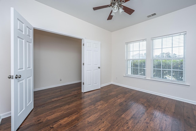 unfurnished bedroom with ceiling fan, dark wood-style flooring, visible vents, and baseboards