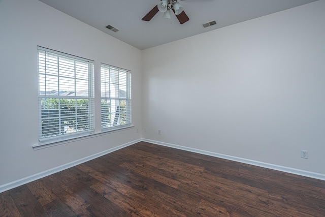 empty room with dark wood-type flooring, visible vents, baseboards, and a ceiling fan