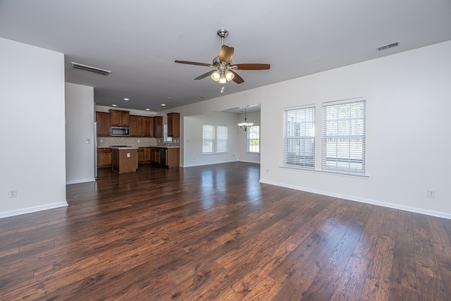 unfurnished living room with visible vents, dark wood finished floors, baseboards, and ceiling fan with notable chandelier