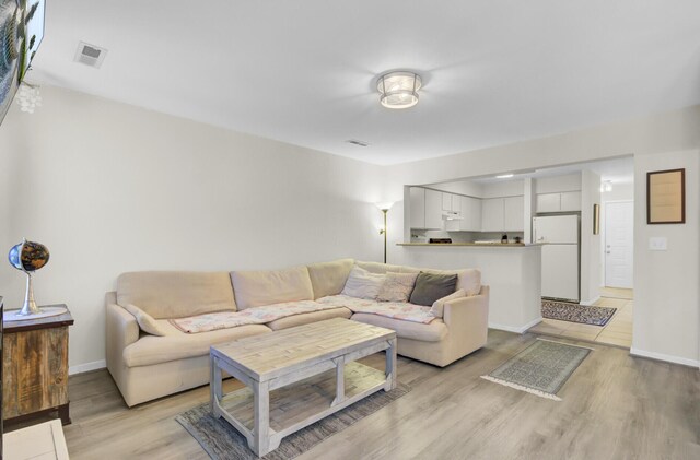 living area with visible vents, light wood-type flooring, and baseboards