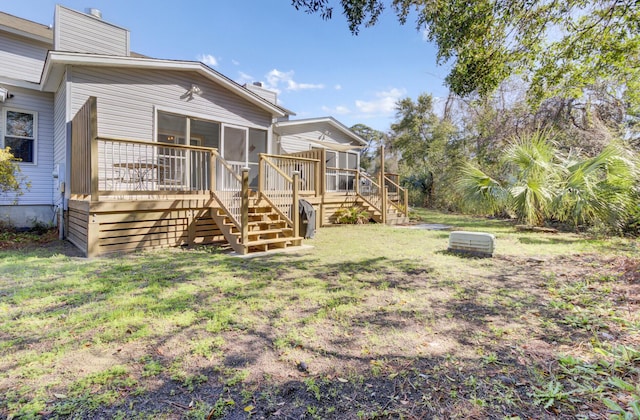 rear view of property featuring stairs, a deck, a lawn, and a sunroom