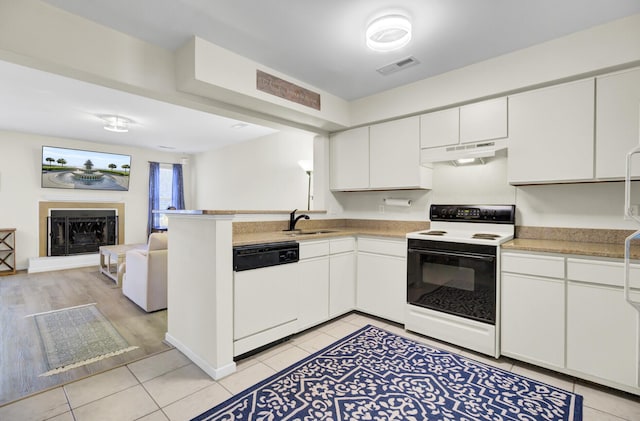 kitchen featuring visible vents, range with electric cooktop, a fireplace with raised hearth, under cabinet range hood, and dishwasher