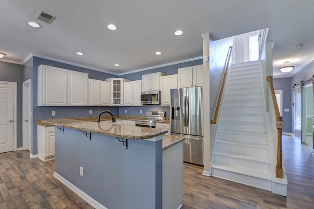 5105 Parrum Ct, Summerville, SC 29485 - kitchen with appliances with stainless steel finishes, crown molding, a barn door, a breakfast bar area, and glass insert cabinets