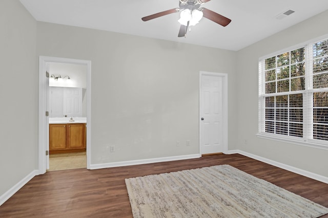 interior space featuring dark wood-style flooring, visible vents, baseboards, and ensuite bathroom