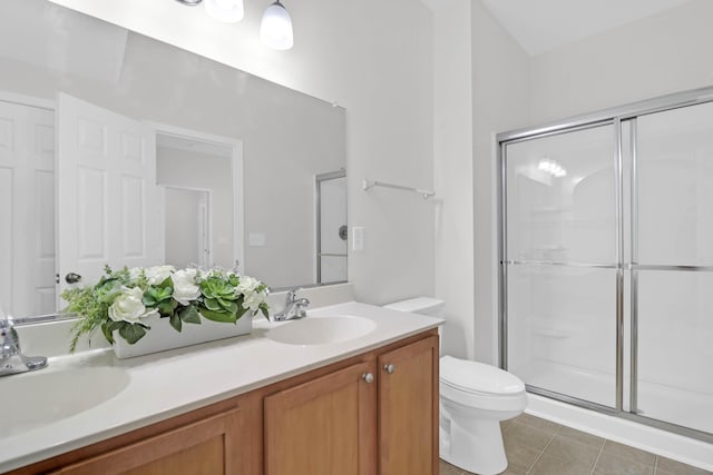 full bath featuring toilet, double vanity, a sink, and a shower with door