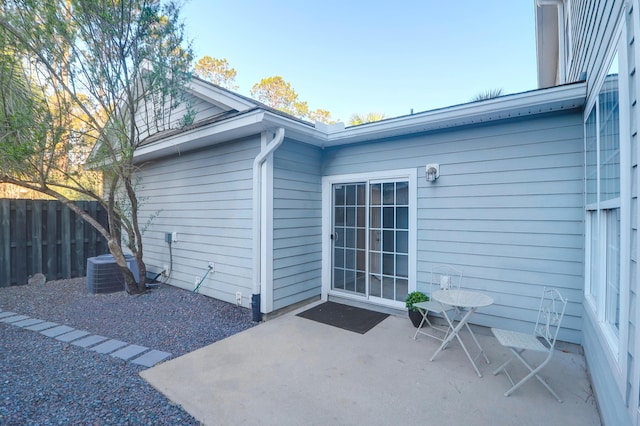 doorway to property with a patio area, fence, and central AC