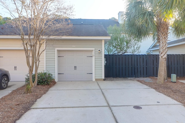 garage with concrete driveway and fence