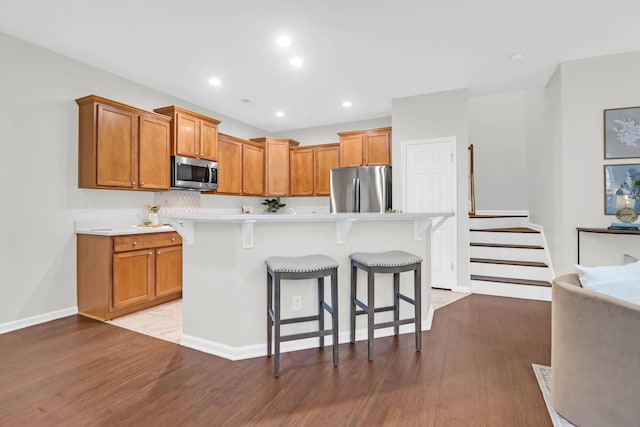 kitchen with light wood-style flooring, a breakfast bar area, stainless steel appliances, and light countertops