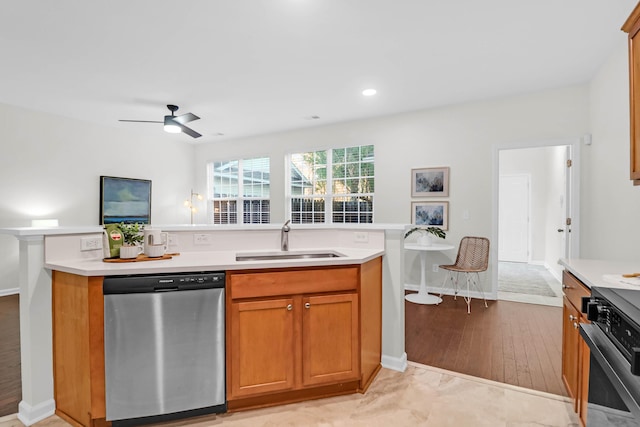 kitchen featuring light countertops, stainless steel dishwasher, a sink, and brown cabinets