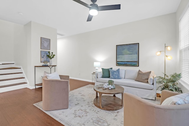 living room with stairs, ceiling fan, wood finished floors, and baseboards