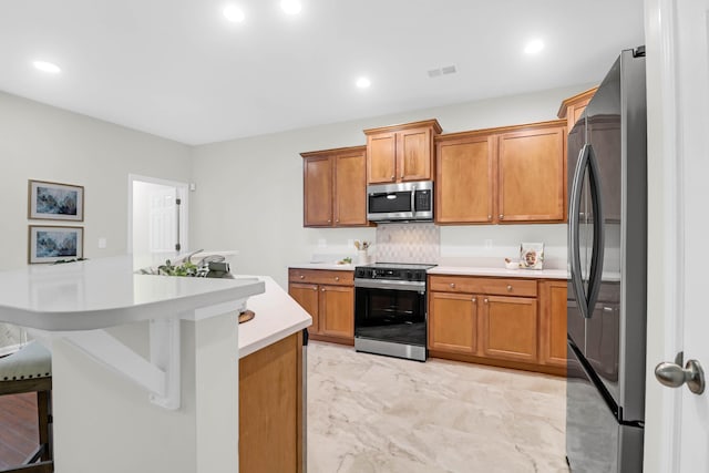 kitchen featuring appliances with stainless steel finishes, light countertops, brown cabinetry, and visible vents