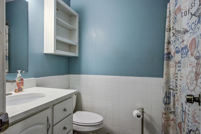 bathroom with vanity, toilet, and tile walls