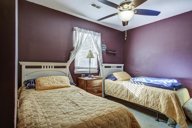 carpeted bedroom featuring ceiling fan and a textured ceiling