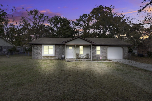 ranch-style home featuring a yard, covered porch, and a garage