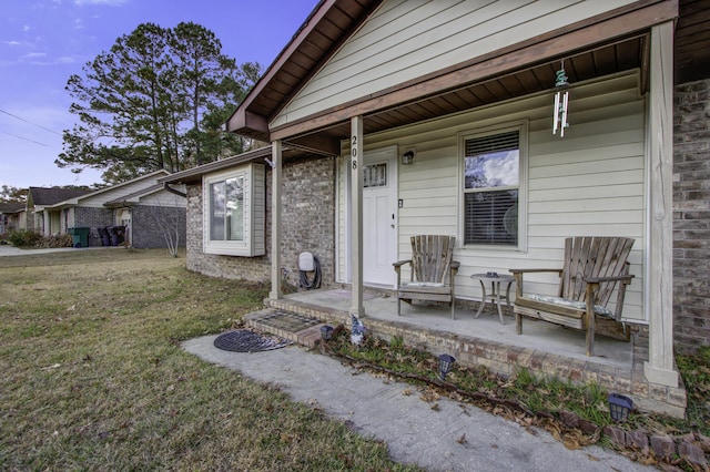 property entrance featuring a lawn and covered porch