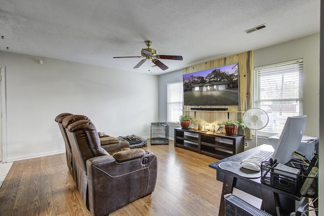 living room featuring hardwood / wood-style floors, ceiling fan, and a textured ceiling