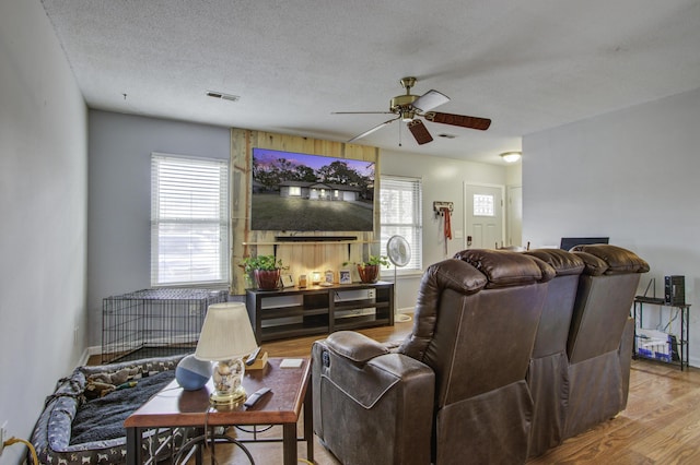 living room with ceiling fan, wood-type flooring, and a textured ceiling