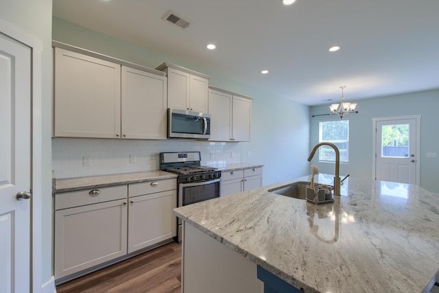 3018 Vincent Astor Dr, Johns Island, SC 29455 - kitchen featuring stainless steel appliances, dark wood-style floors, backsplash, a kitchen island with sink, and light stone counters