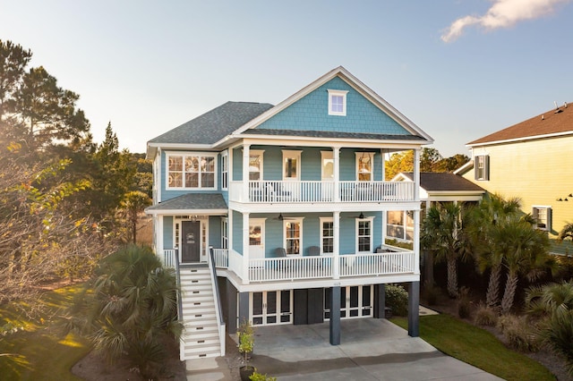 coastal home featuring a balcony, a porch, and a carport