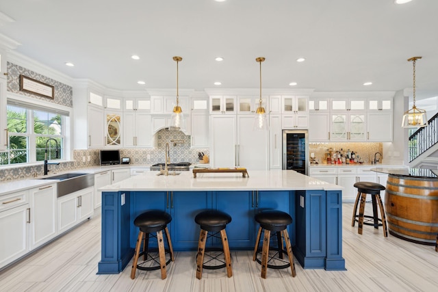 kitchen featuring crown molding, a kitchen island with sink, sink, and pendant lighting