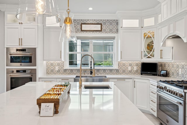 kitchen featuring tasteful backsplash, stainless steel appliances, sink, pendant lighting, and white cabinetry