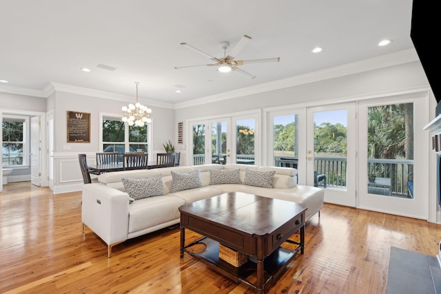 living room with ceiling fan with notable chandelier, light hardwood / wood-style floors, ornamental molding, and french doors