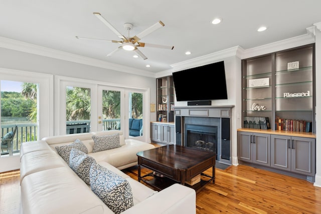 living room featuring a fireplace, crown molding, plenty of natural light, and light hardwood / wood-style floors