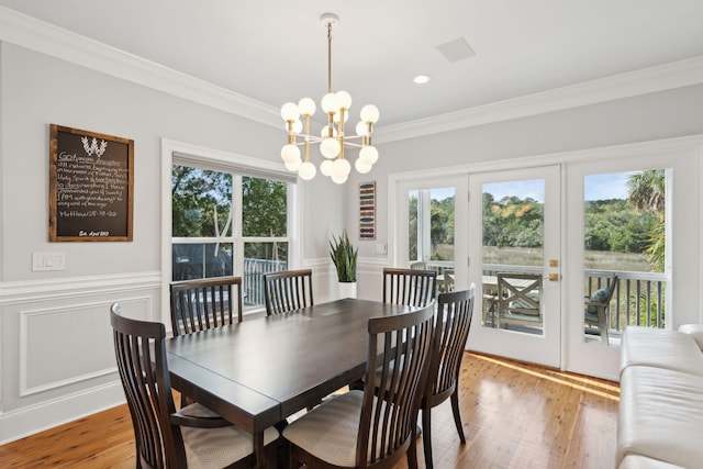 dining room with crown molding, french doors, light hardwood / wood-style floors, and an inviting chandelier