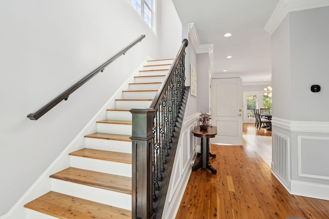 stairway featuring hardwood / wood-style flooring, crown molding, and a notable chandelier