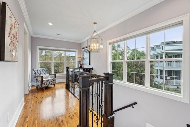 hallway with a chandelier, hardwood / wood-style flooring, and ornamental molding