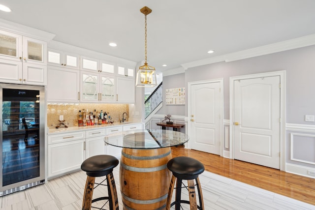 kitchen featuring white cabinetry, pendant lighting, a breakfast bar area, a kitchen island, and ornamental molding