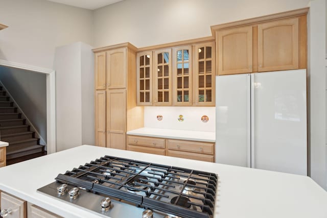 kitchen with white refrigerator, light brown cabinetry, and stainless steel gas stovetop