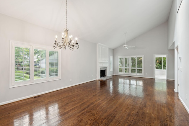 unfurnished living room with a healthy amount of sunlight, ceiling fan with notable chandelier, high vaulted ceiling, and dark hardwood / wood-style flooring