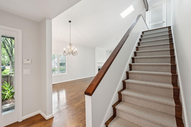 stairway with hardwood / wood-style floors and an inviting chandelier