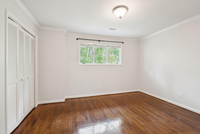 unfurnished bedroom featuring crown molding, dark hardwood / wood-style floors, and a closet