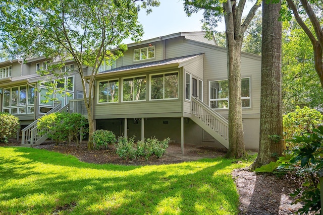 rear view of property with a sunroom and a lawn