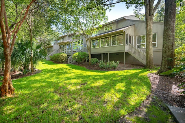 back of house featuring a sunroom and a lawn