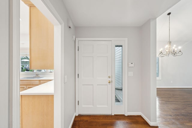 entrance foyer with a notable chandelier, sink, and dark hardwood / wood-style flooring