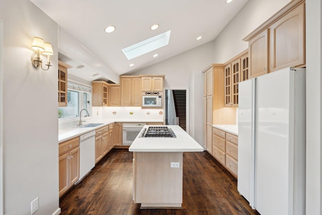 kitchen with lofted ceiling with skylight, white appliances, light brown cabinetry, a kitchen island, and sink