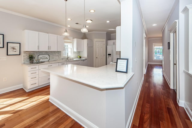 2517 Charter Oaks Dr, Mount Pleasant, SC 29466 - kitchen with white fridge with ice dispenser, ornamental molding, decorative backsplash, white cabinetry, and wood finished floors
