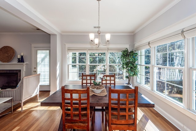 2517 Charter Oaks Dr, Mount Pleasant, SC 29466 - dining area with healthy amount of natural light, wood finished floors, a chandelier, ornamental molding, and a tile fireplace