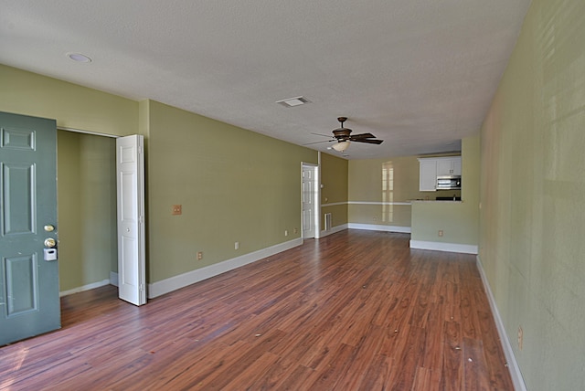 empty room featuring a textured ceiling, dark wood-type flooring, and ceiling fan